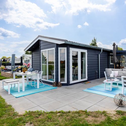 Aussenansicht Chalet  mit Sitzlounge, Esstisch , Zugang Wohnzimmer und Ausblick auf See